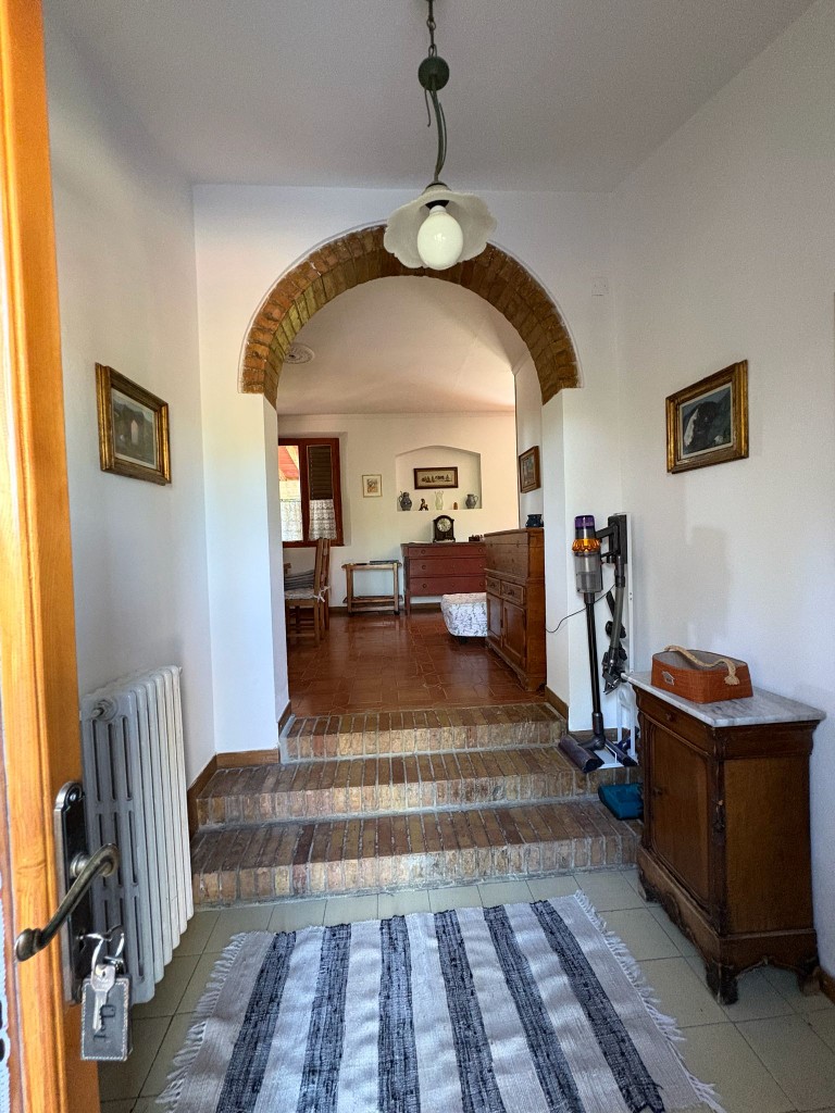 Ingresso con arco in mattoni e mobili antichi a Villa Talciona