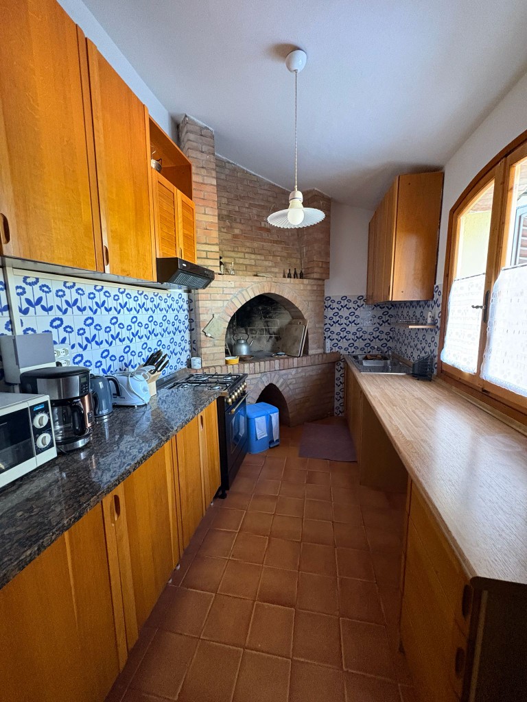 Cucina rustica toscana con mobili in legno e forno a legna in mattoni a Villa Talciona