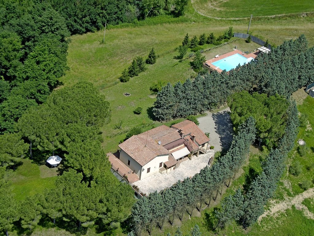 Vista aerea di Villa Talciona con piscina, terrazza in cotto, pini e campagna del Chianti