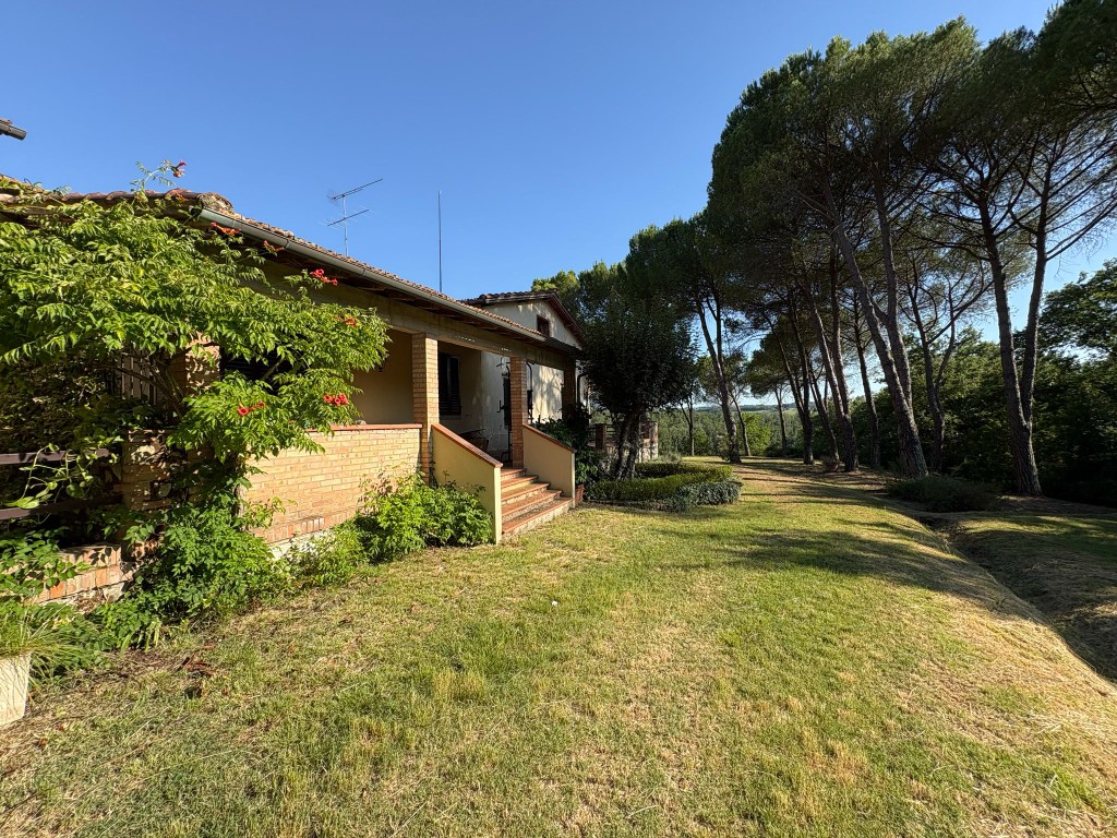 Vista esterna di Villa Talciona con gradini del giardino, pini e cielo toscano